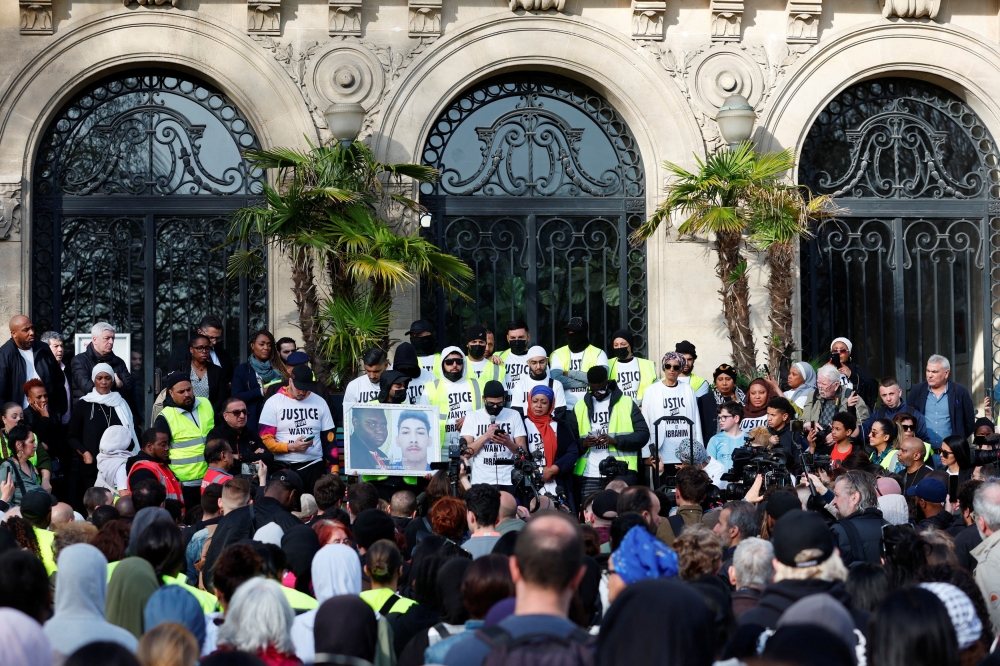 People attend a protest while holding a banner with pictures of Wanys and Ibrahim to pay tribute to Wanys, a youth who died after he failed to stop his motorbike after police had ordered him to do so in Aubervilliers, and Ibrahim, an injured passenger, during a silent march in La Courneuve, Paris suburb, France, March 21, 2024. — Reuters pic