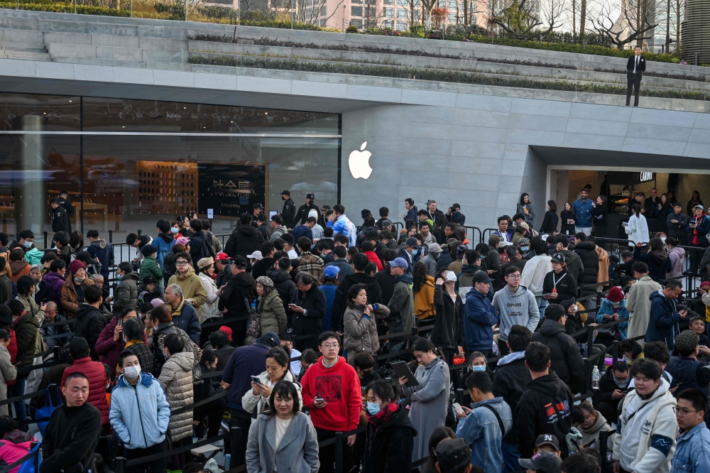 Customers gather outside Shanghai's new Apple retail store before its opening in Shanghai on March 21, 2024. Chinese Apple superfans jostled to enter the smartphone maker's newest store as it opened on March 21 night -- but they were upstaged by dozens of retirees eager to nab commemorative freebies. — AFP pic