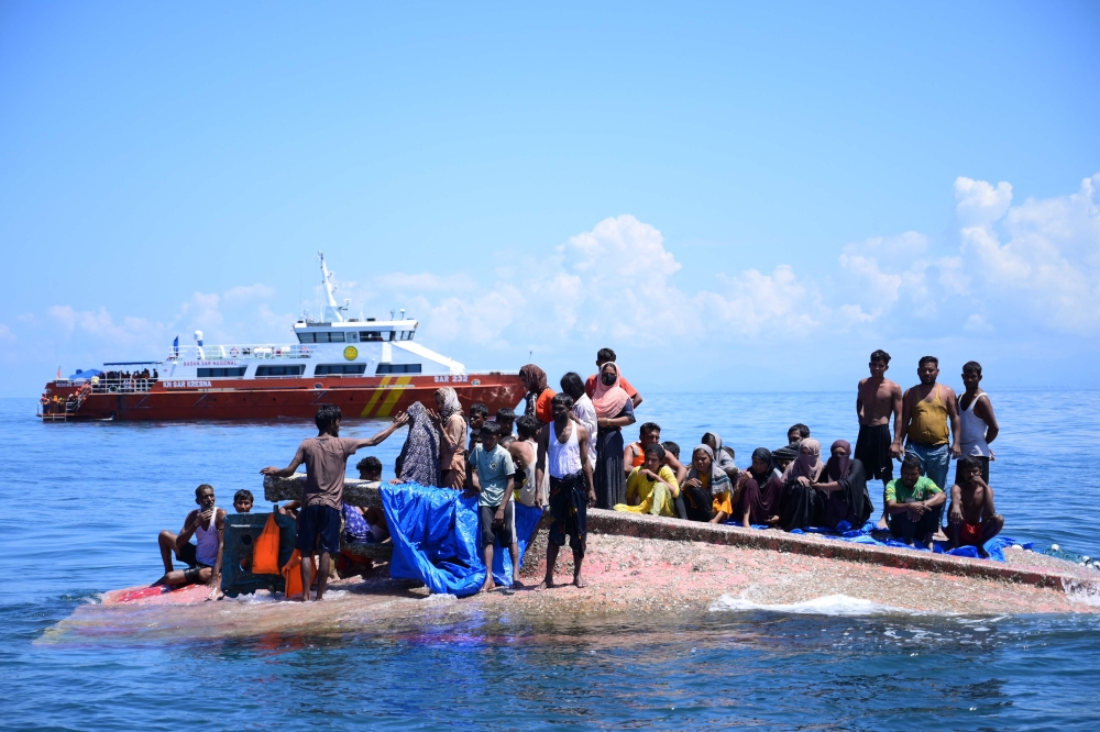 Rohingya refugees wait to be rescued from the hull of their capsized boat as a National Search and Rescue Agency (Basarnas) vessel approaches in waters some 16 nautical miles (29 kilometers) off west Aceh on March 21, 2024. — AFP pic