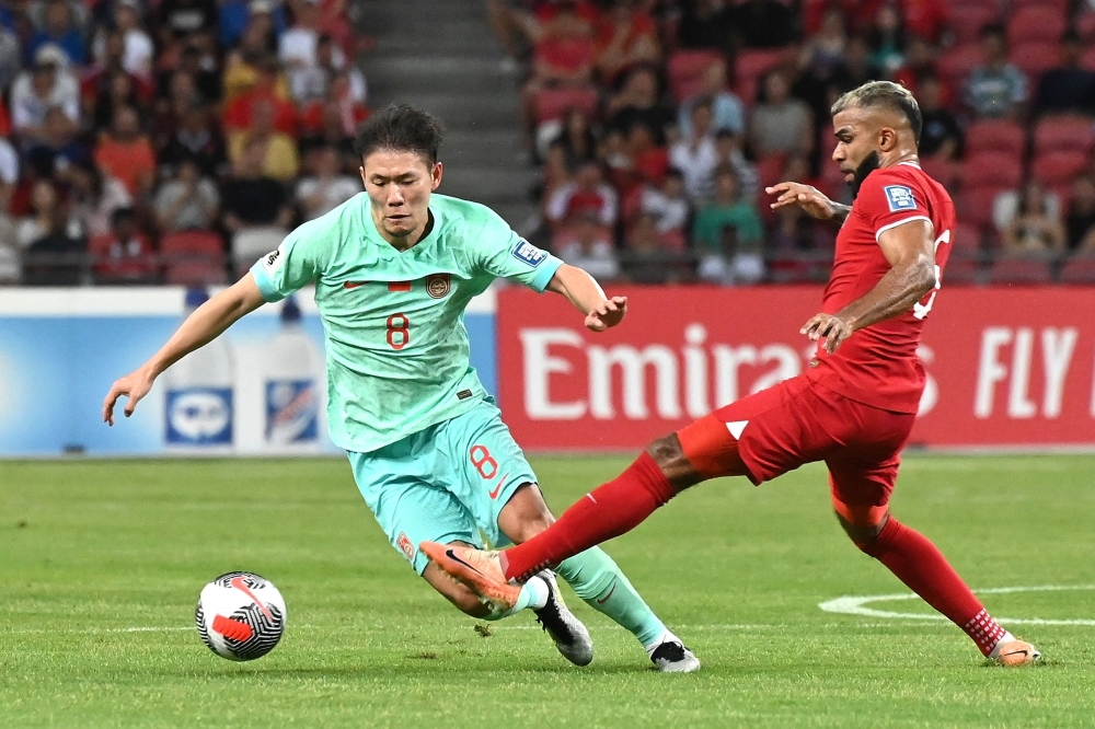 China's Li Yuanyi (left) and Singapore's Anumanthan Kumar (right) compete for the ball during the Fifa World Cup 2026 qualifier football match between Singapore and China at the National Stadium in Singapore March 21, 2024. — AFP pic 