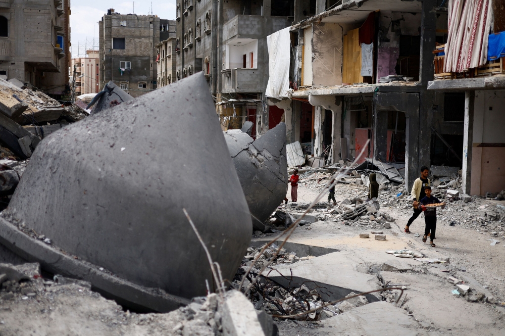 A boy holds a tray with food as he walks near destroyed houses, amid the ongoing conflict between Israel and Hamas, in Rafah, in the southern Gaza Strip, March 22, 2024. ― Reuters pic