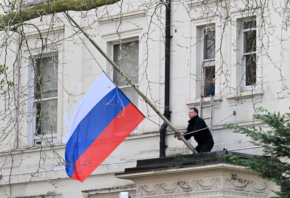 A person adjusts the national flag of Russia, flying at half-mast, outside the Russian embassy in London on March 23, 2024, a day after a gun attack in Krasnogorsk, outside Moscow. Camouflaged assailants opened fire at the packed Crocus City Hall in Moscow's northern suburb of Krasnogorsk on March 22, 2024, ahead of a concert by Soviet-era rock band Piknik in the deadliest attack in Russia for at least a decade. — AFP pic