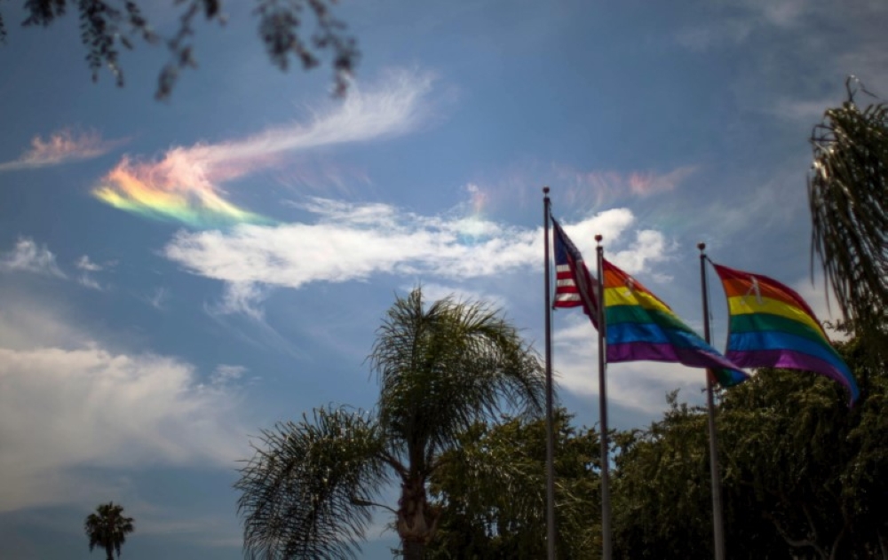 File photo of a rainbow seen in the sky behind LGBT pride flags and the US flag in West Hollywood, California June 26, 2015. - Reuters pic