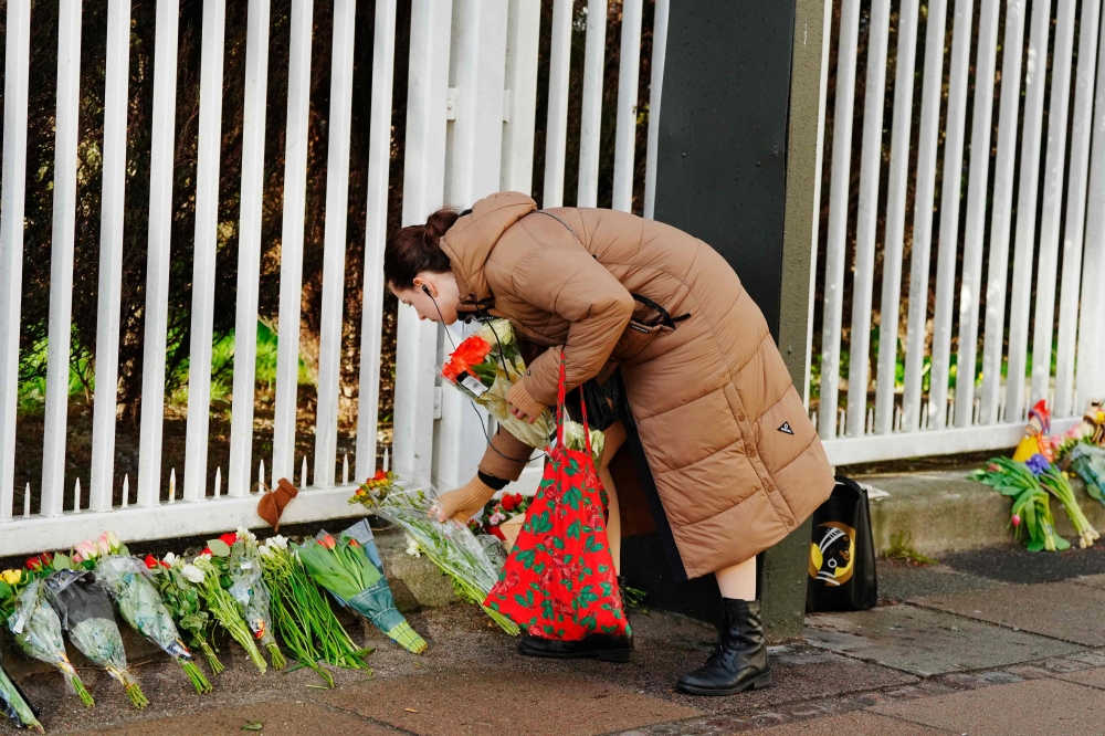 A woman lays flowers at a makeshift memorial in front of the Russian Embassy in Copenhagen, Denmark, on March 23, 2024, a day after a gun attack in Krasnogorsk outside Moscow. — AFP pic