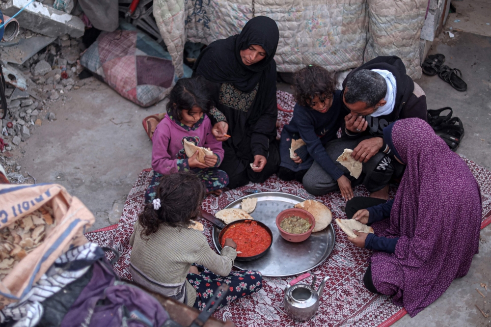 Members of the Rabaya family break their fast amidst the rubble of their home, which was destroyed by an Israeli strike, during the Muslim holy month of Ramadan in Rafah on March 23, 2024, amid ongoing battles between Israel and the militant group Hamas. — AFP pic