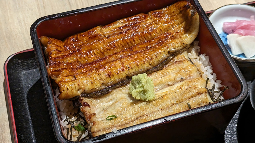 A tale of two halves of an eel: on top is 'kabayaki', unagi grilled with 'tare' and on the bottom is 'shirayaki', unagi grilled with just salt instead of 'tare'.