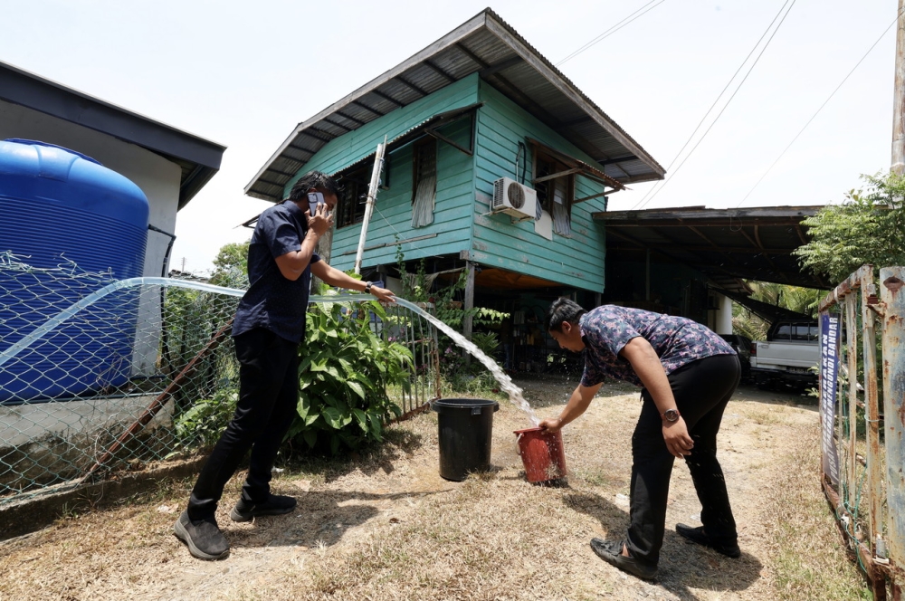 Papar MP's office staff helping local residents by distributing clean water in Kampung Kuala Papar, March 14, 2024. The prolonged drought has disrupted the water supply in several villages in the district. — Bernama pic