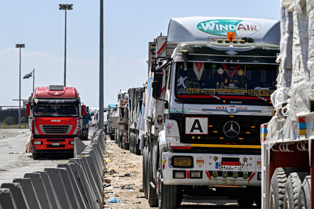 Egyptian trucks carrying humanitarian aid bound for the Gaza Strip queue outside the Rafah border crossing on the Egyptian side. — AFP pic