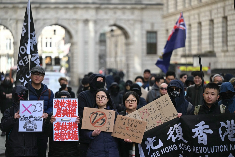 People hold up placards at a demonstration outside the Foreign and Commonwealth Development Office in London to protest the introduction of the Article 23 National Security Law in Hong Kong. — AFP pic