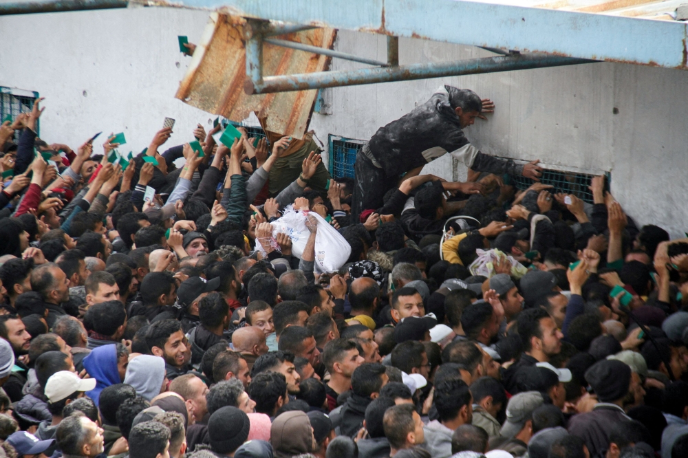 Palestinians gather to receive aid outside an UNRWA warehouse as Gaza residents face crisis levels of hunger, amid the ongoing conflict between Israel and Hamas, in Gaza City March 18, 2024. — Reuters pic