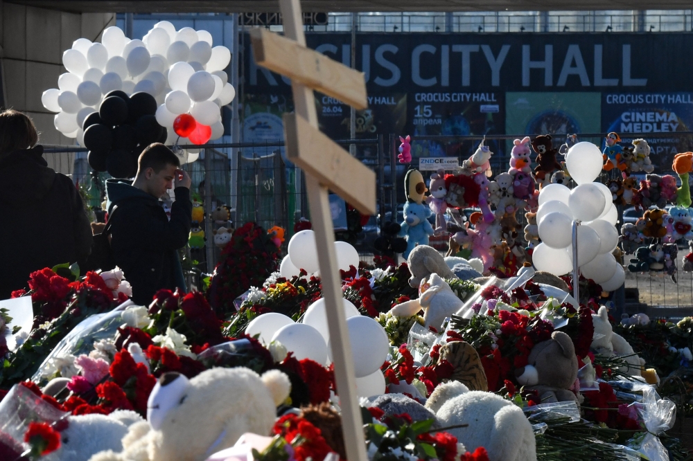 People bring flowers to a makeshift memorial in front of the burnt-out Crocus City Hall concert venue in Krasnogorsk, outside Moscow, on March 25, 2024. — AFP pic