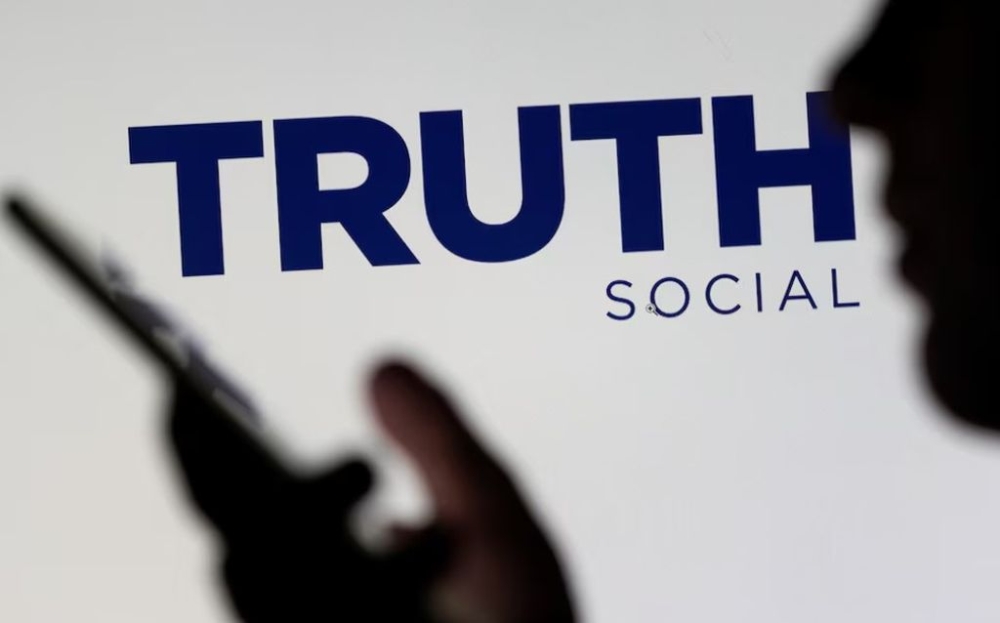 The Truth social network logo is seen displayed behind a woman holding a smartphone in this picture illustration taken February 21, 2022. — Reuters pic