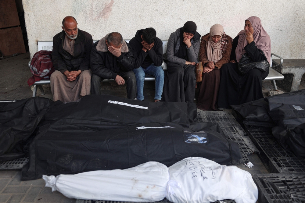 Palestinians mourn over the covered bodies of relatives, killed in overnight Israeli bombardment, at the al-Najjar hospital in Rafah. — AFP pic