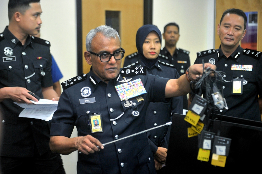 Bukit Aman Commercial Crime Investigation Department (CCID) director Datuk Seri Ramli Mohamed Yoosuf with video encoders seized in the raid. He said the detained individuals, aged 53 and 57, are believed to be the masterminds behind the syndicate. — Bernama pic 
