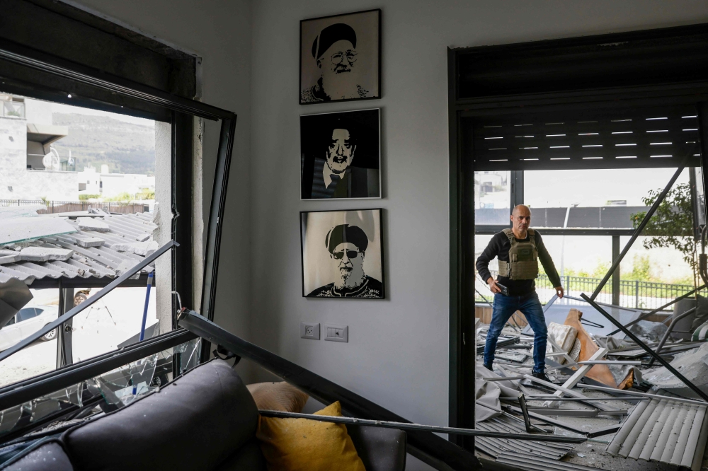An Israeli man checks a building that was hit by a Hezbollah rocket in Kiryat Shmona in northern Israel near the Lebanon border, on March 27, 2024. — AFP pic