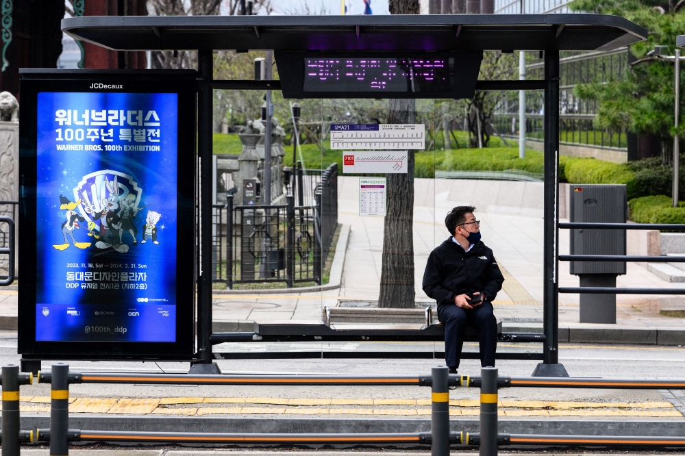 A man sits at a bus stop in Seoul on March 28, 2024, as unionised Seoul Bus drivers went on strike, bringing over 7,200 buses to a full stop and disrupting commute hours in the South Korean capital over a wage hike dispute. — AFP pic