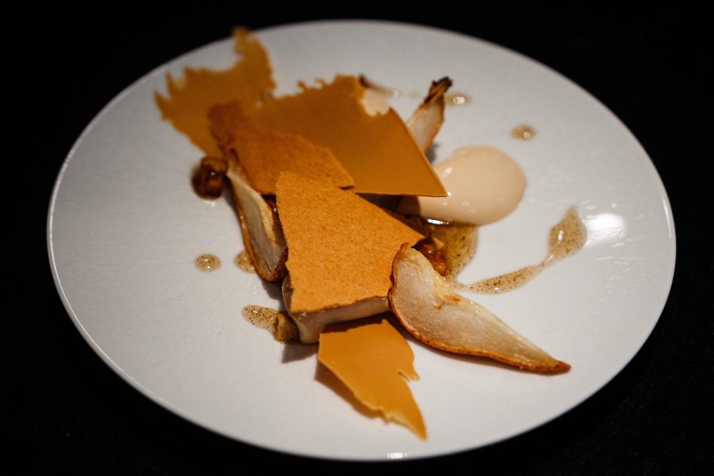 A photograph taken in Paris on March 1, 2024, shows a pure fondant dessert with 'blond' chocolate, oven-roasted apples and a Tahitian vanilla cream prepared by French pastry chef and creative director of Valrhona chocolaterie Frederic Bau at Valrhona chocolatier. A fourth colour of chocolate, 'blond', with a highly caramelised taste, was born in France in 2012 and is spreading among pastry chefs without having any chance of being legally recognised, even though the Swiss are also claiming a similar invention, this time 'pink'. — AFP pic