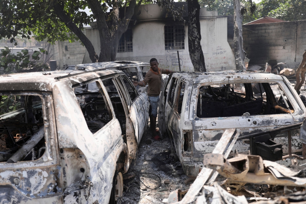 A man looks at the charred remains of vehicles near the presidential palace, after they were set on fire by gangs, as violence spreads and armed gangs expand their control over the capital, in Port-au-Prince, Haiti March 25, 2024. — Reuters pic