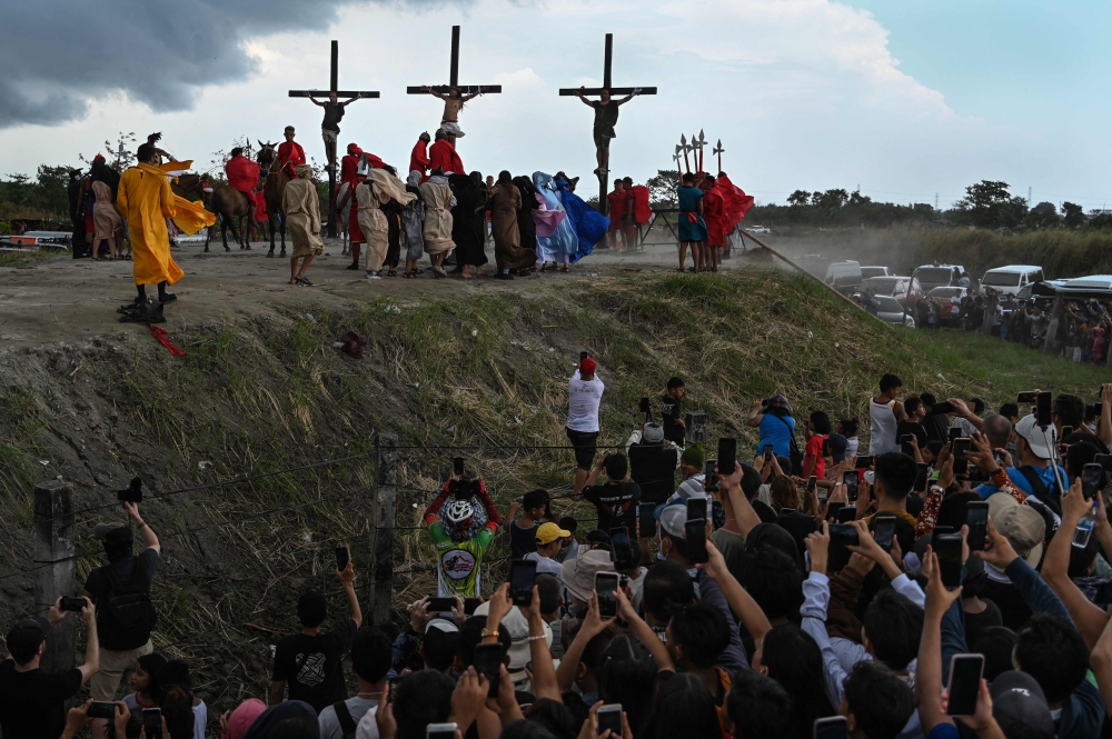 People watch the re-enactment of the crucifixion of Jesus Christ on Good Friday in San Fernando, Pampanga province on March 29, 2024. — AFP pic