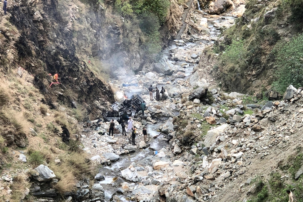 Security officials inspect the wreckage of a vehicle which was carrying Chinese nationals that plunged into a deep ravine off the mountainous Karakoram Highway after a suicide attack near Besham city in the Shangla district of Khyber Pakhtunkhwa province on March 26, 2024. — AFP pic