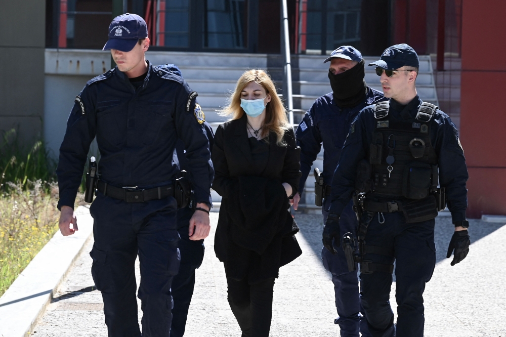 Police officers escort to court Roula Pispirigou (C), a 35-year-old woman prosecuted for having killed her three daughters in three years, in Athens on March 29, 2024. — AFP pic