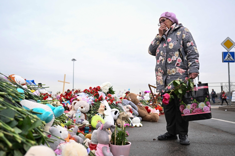 A woman reacts as she stands at a makeshift memorial in front of the Crocus City Hall in Moscow's northern suburb of Krasnogorsk March 29, 2024, a week after a deadly attack by gunmen on a Moscow concert hall killed at least 143 people and wounded dozens more. — AFP pic