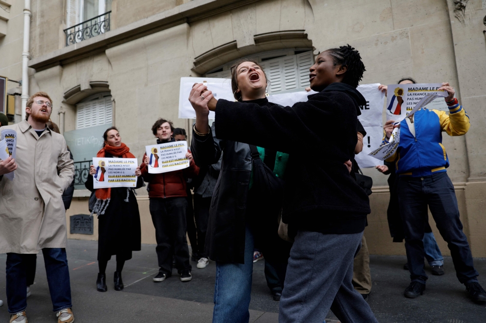 Demonstrators dance during a rally in front of the Rassemblement National (RN) organised by the French association SOS Racisme in Paris on March 24, 2024, in support of Aya Nakamura, following the numerous racist attacks on the French-Malian singer, who was mentioned as a possible participant in the opening ceremony of the 2024 Paris Olympic Games. — AFP pic