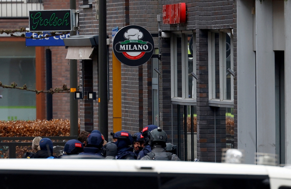 Dutch police officers stand near the Cafe Petticoat, where several people are being held hostage in Ede, Netherlands March 30, 2024. — Reuters pic  