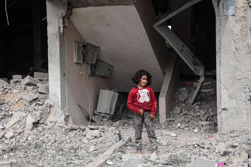 A Palestinian child inspects the damage to a building after overnight Israeli bombardment in Rafah in the southern Gaza Strip on March 29, 2024, amid the ongoing conflict between Israel and Hamas.— AFP pic