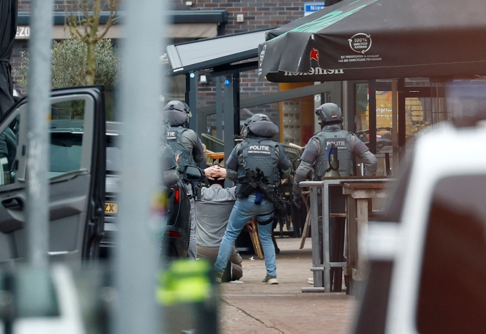 Dutch police officers detain a person near the Cafe Petticoat, where several people are being held hostage in Ede, Netherlands March 30, 2024. — Reuters pic  