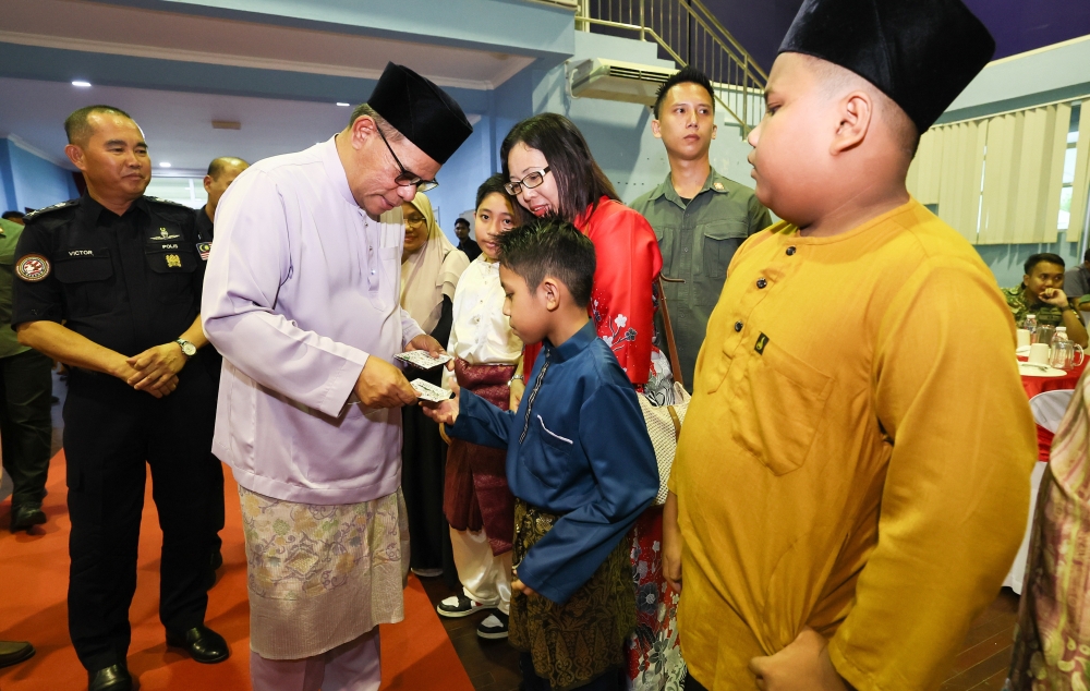 Home Minister Datuk Seri Saifuddin Nasution Ismail presenting duit Raya to children of security personnel in Lahad Datu. — Bernama pic