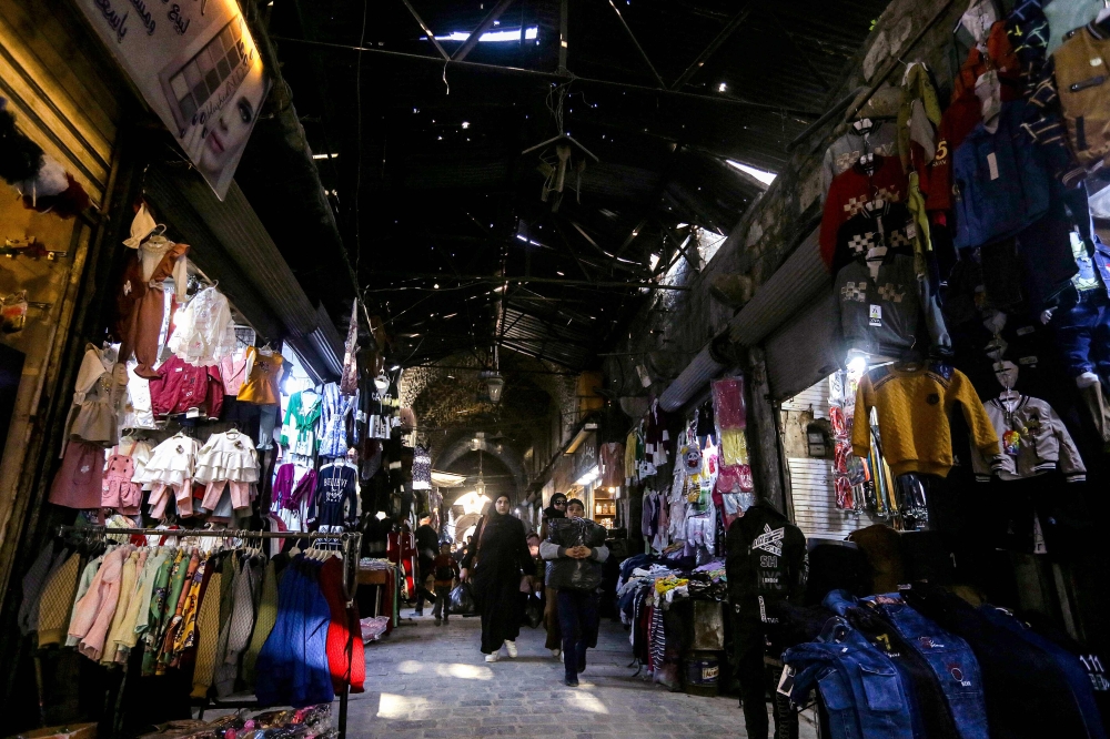 This photo depicts a scene of people walking past vendors’ shops along a restored alley in the Souk al-Atik bazaar, which was formerly damaged during the Syrian conflict, in Syria's northern city of Aleppo on March 30, 2024. — AFP pic