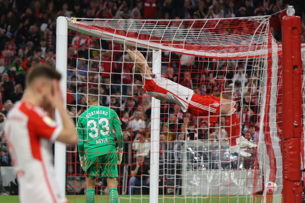 Bayern Munich’s English forward Harry Kane swings from the goal post after missing a chance to score past Dortmund’s German goalkeeper Alexander Meyer during the German first division Bundesliga football match FC Bayern Munich v BVB Borussia Dortmund in Munich. — AFP pic