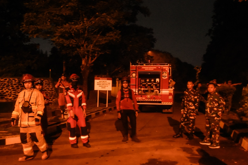 Firefighters stand outside the entrance to a military ammunition warehouse, in Bekasi, West Java, on March 30, 2024. — AFP pic