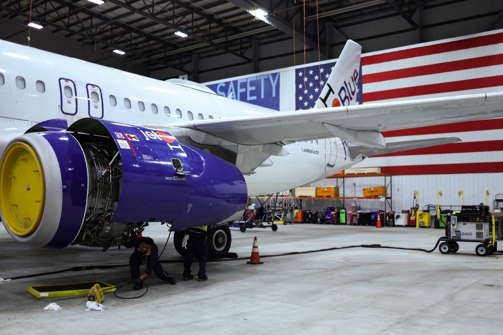File photo of employees of Jet Blue airlines working on an engine of an Airbus A320 passenger aircraft in a maintenance hangar of the company at JFK International Airport in New York on March 4, 2024, prior of a Career Discovery Week event. — AFP pic