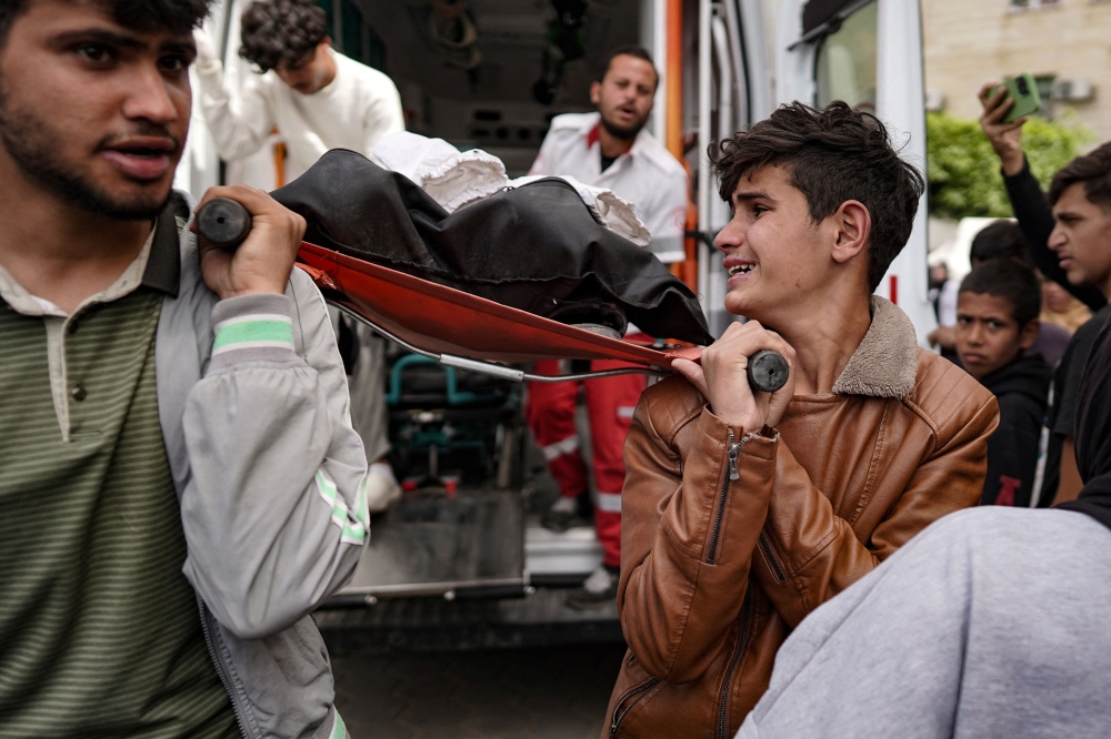 File photo of relatives carrying the body of a Palestinian man from an ambulance to the Al-Aqsa Martyrs hospital in Deir al-Balah in the central Gaza Strip after he was reportedly killed in Israeli bombardment, on March 28, 2024. — AFP pic