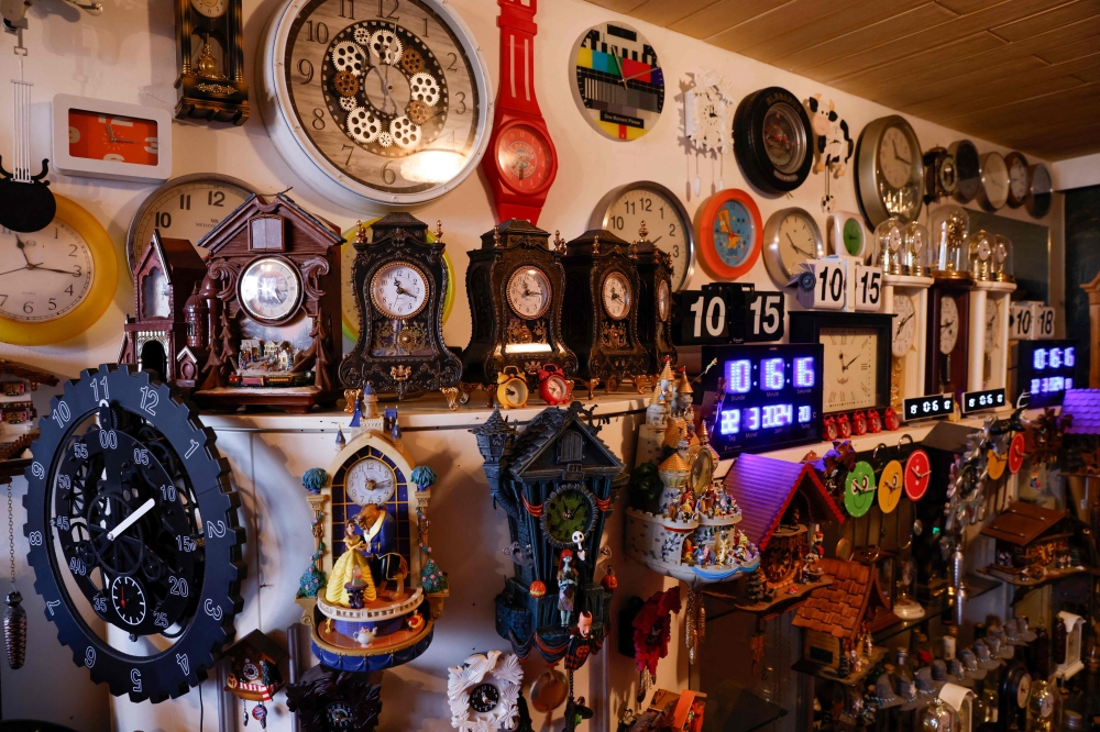 Werner Stechbarth poses inmid his collection of clocks in his living room in Munich March 22, 2024. The early year move to daylight saving time is a busy period for the pensioner, who takes it upon himself to adjust every one of his timepieces. — AFP pic