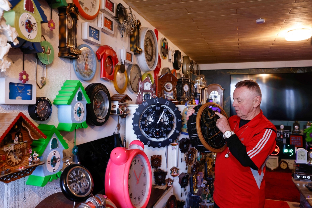Werner Stechbarth sets a clock in his living room in Munich March 22, 2024. — AFP pic