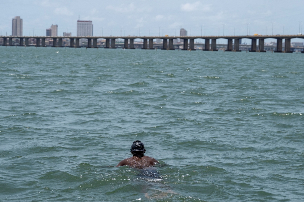 Akinrodoye Samuel swims to complete his ambitious endeavor to swim the 11.8 km stretch of the Third Mainland Bridge, advocating for the theme 'Swim Against Suicide And Depression' in Lagos, Nigeria, March 30, 2024. — Reuters pic  