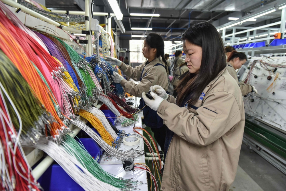 Employees work on a wire harness production line at a factory which supplies car accessories to the automotive market in Fuyang, in eastern China's Anhui province on March 28, 2024. — AFP pic