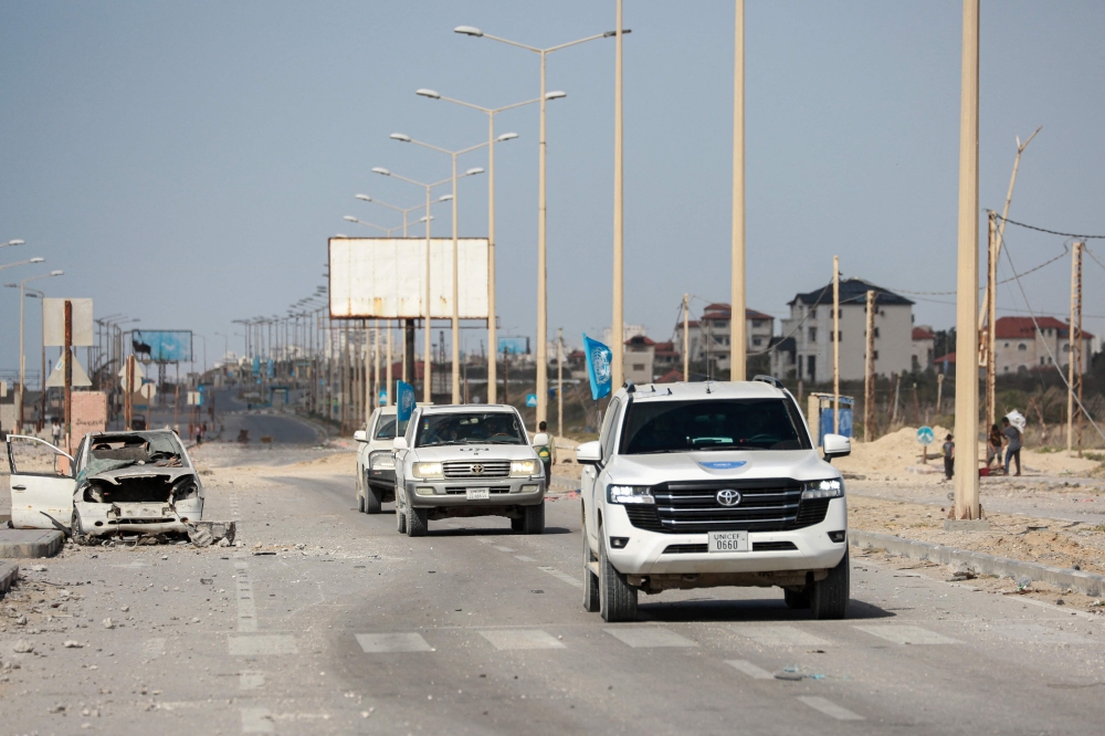 UN vehicles drive past a destroyed car on a road in Gaza City on April 1, 2024, amid the ongoing battles Israel and the Hamas militant group. — AFP pic