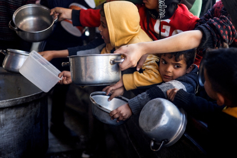 Palestinian children wait to receive food cooked by a charity kitchen amid shortages of food supplies, as the conflict between Israel and the Palestinian Islamist group Hamas continues, in Rafah, in the southern Gaza Strip, March 5, 2024. — Reuters pic
