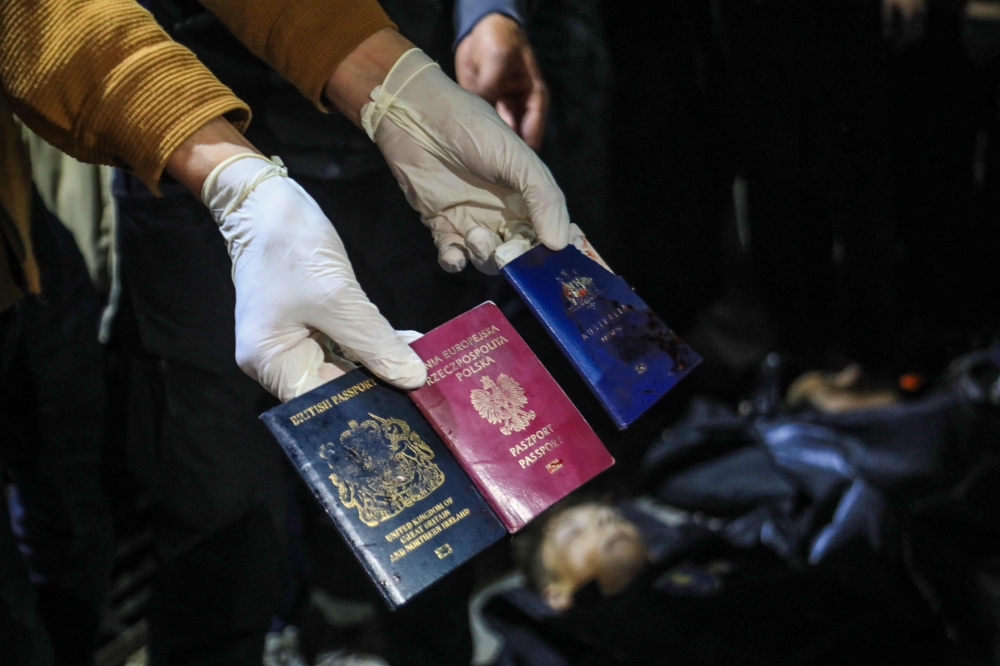 A man displays British, Polish, and Australian passports next to the bodies of World Central Kitchen workers at Al-Aqsa Hospital in Deir al-Balah, Gaza Strip. — AFP pic 