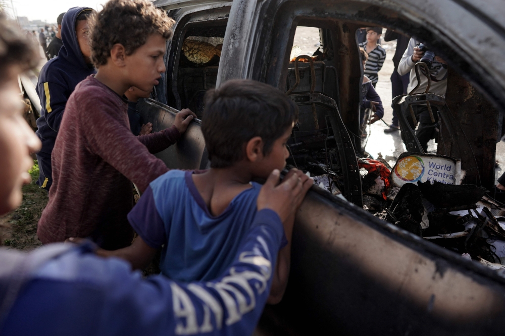 Children gathered around the vehicle used by aid group, World Central Kitchen, that was hit by an Israeli bomb. — AFP pic