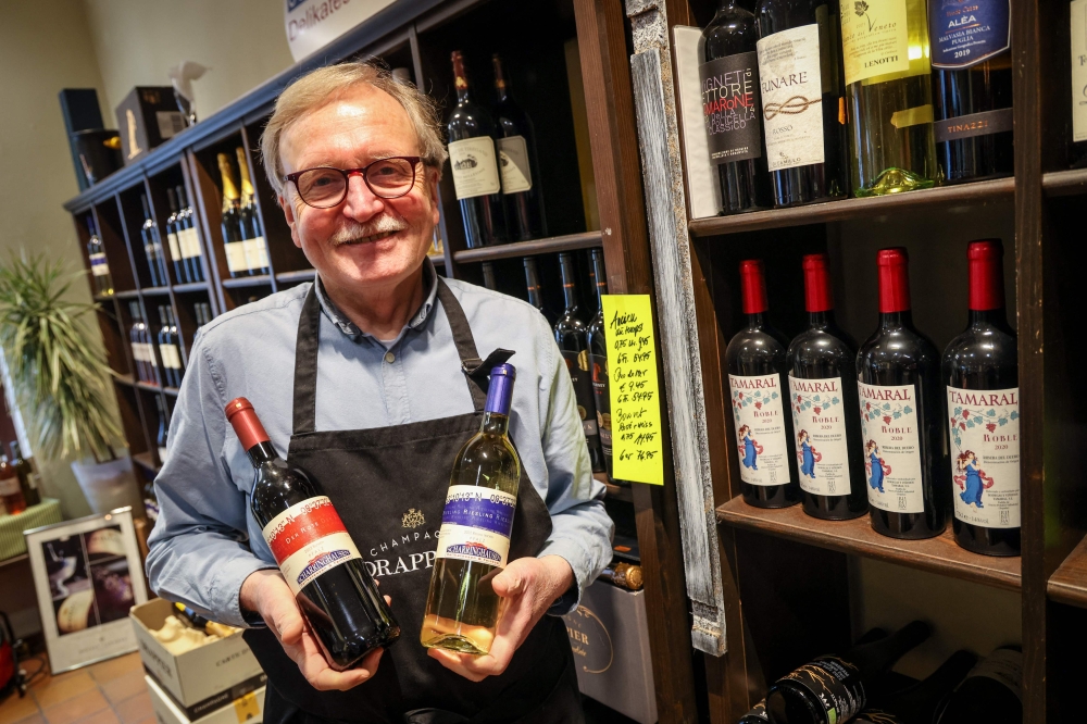 Shop owner Juergen Scharringhausen holds bottles of his own Scharringhausen branded wine at his delicatessen shop in Bremen-Vegesack, Germany, on March 15, 2024. — AFP pic