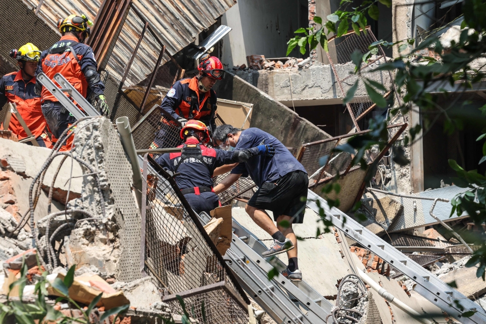 This photo taken by Taiwan's Central News Agency (CNA) on April 3, 2024 shows emergency workers assisting a survivor after he was rescued from a damaged building in New Taipei City, after a major earthquake hit Taiwan's east. — CNA / AFP pic