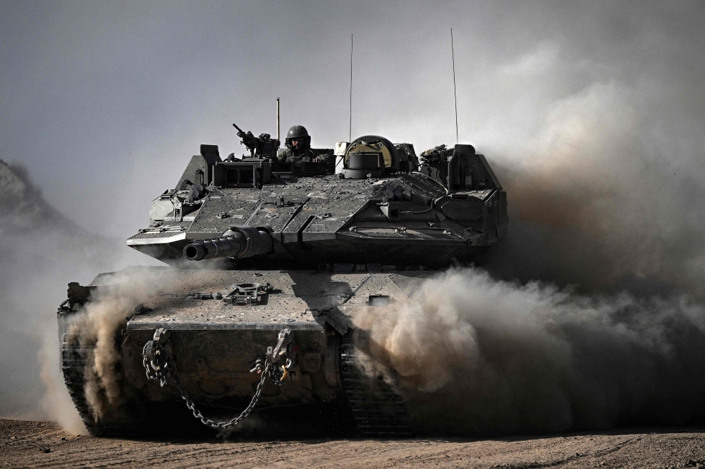 An Israeli army battle tank moves in an area along the border with the Gaza Strip and southern Israel. — AFP pic