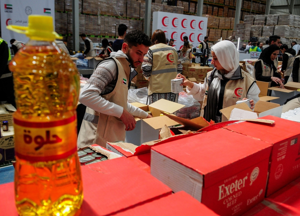 Volunteers from Emirates Red Crescent prepare parcels with humanitarian aid for Gaza to be transferred through the Rafah border crossing. — Reuters pic
