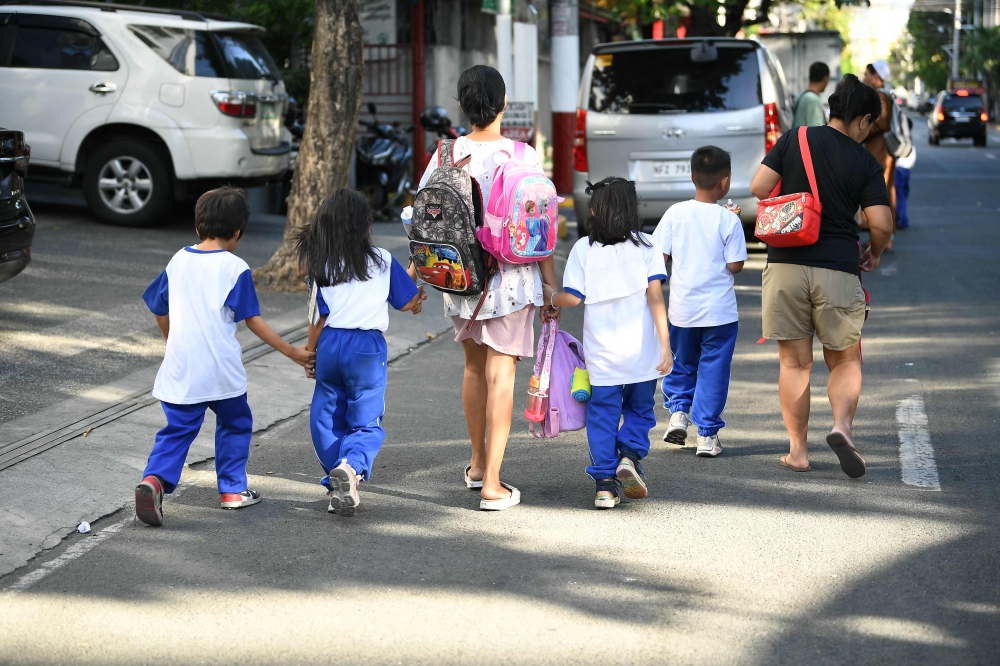 Parents accompany their children from school after their classes in Manila on April 5, 2024. Thousands of schools in the Philippines suspended in-person classes on April 5, the education department said, as parts of the tropical country endured dangerously high temperatures. — AFP pic