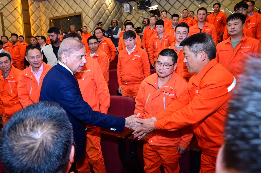 In this handout photograph taken and released by the Pakistan's Press Information Department (PID) on April 1, 2024, shows Pakistan's Prime Minister Shehbaz Sharif (3rd left) interacts with engineers of the China Gezhouba Group Company (CGGC) working at the Dasu Hydropower project in Upper Kohistan district of Khyber Pakhtunkhwa province. — Pakistan's Press Information Department handout pic via AFP